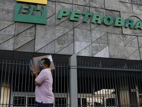Homem carregando caixa passando em frente à fachada da Petrobras