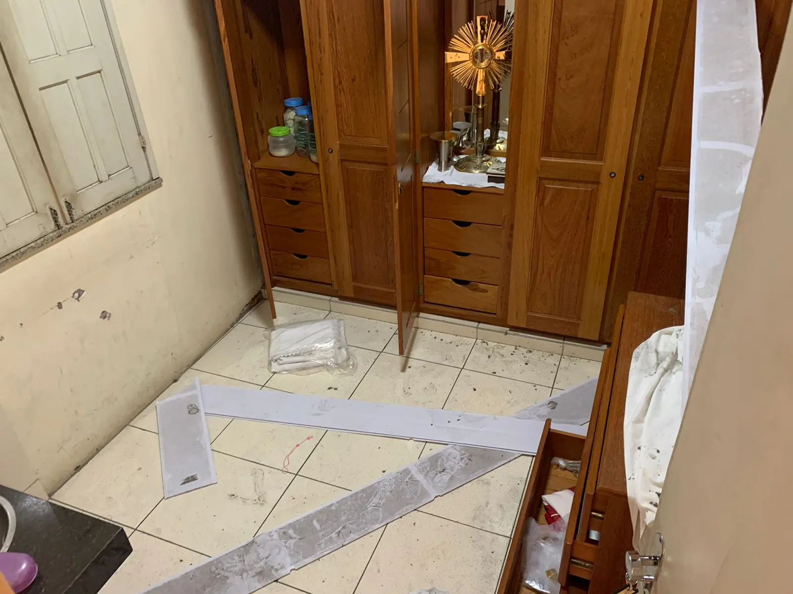 Imagem mostra uma sala da Paróquia Jesus, Maria, José completamente violada. Armários com as portas abertas, coisas quebradas no chão.