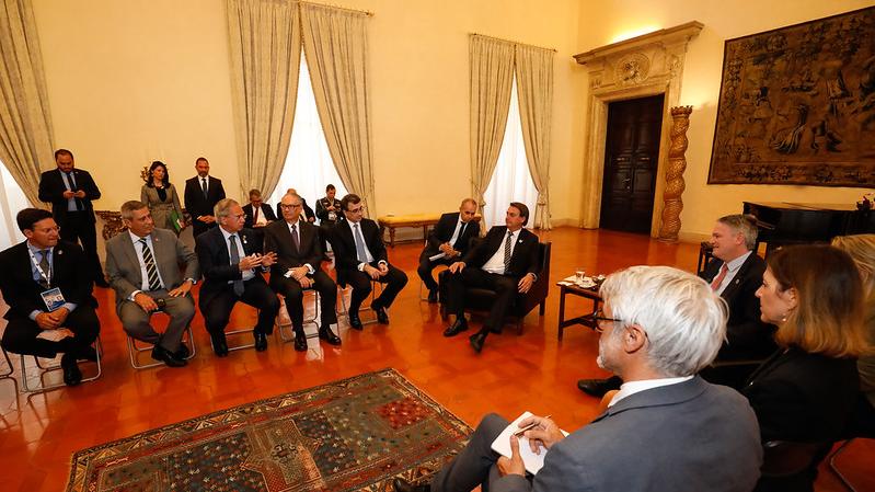 O presidente Jair Bolsonaro está sentado numa poltrona numa sala onde estão reunidos os líderes do G20.