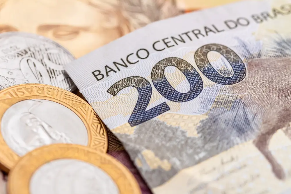 A imagem mostra uma cédula de 200 reais ao lado de moedas.