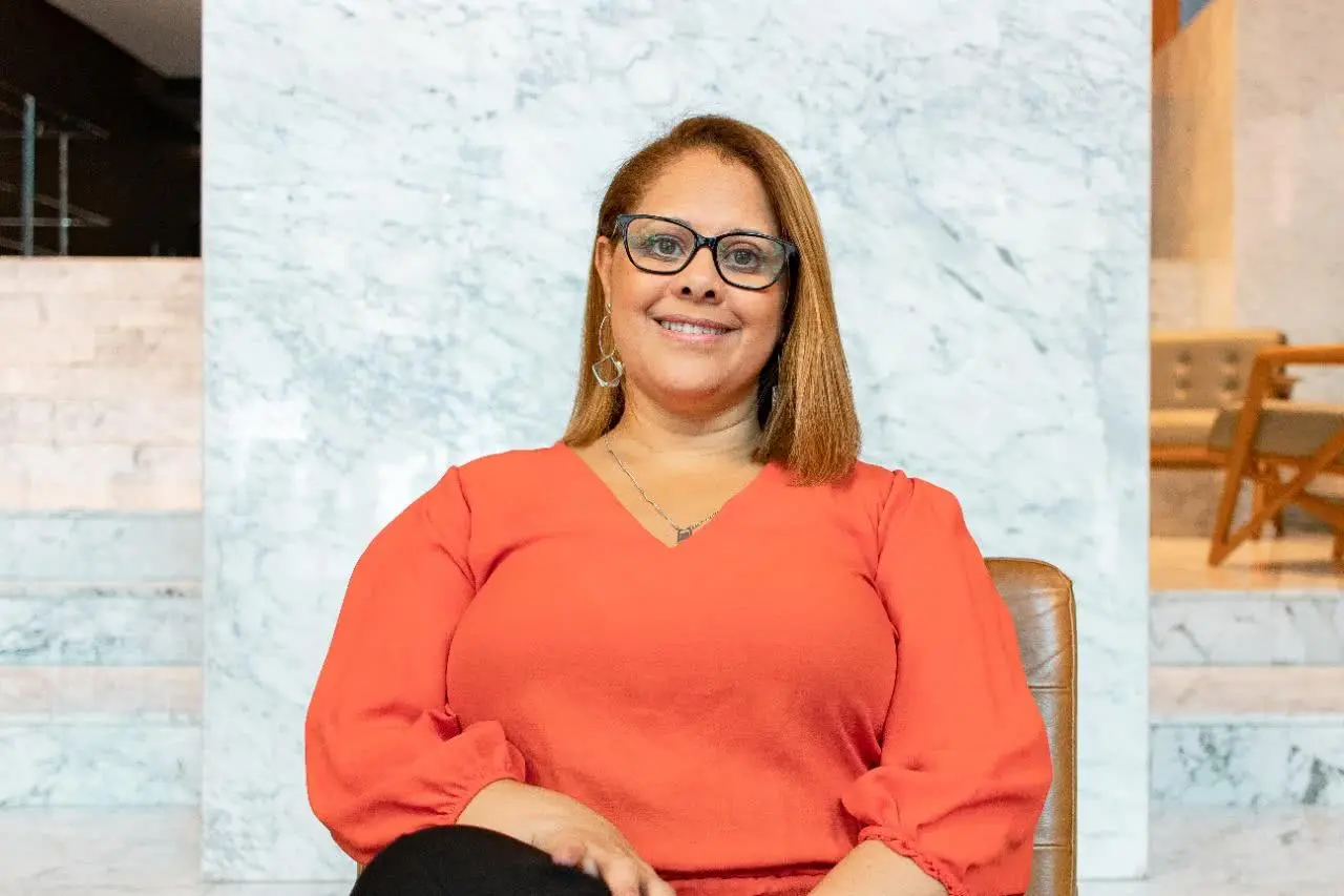 Psicanalista Andréa Ladislau posando para a foto, usando óculos e blusa na cor laranja