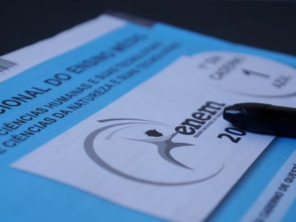 A imagem mostra um caderno de respostas azul do Exame Nacional do Ensino Médio (Enem) e uma caneta preta.