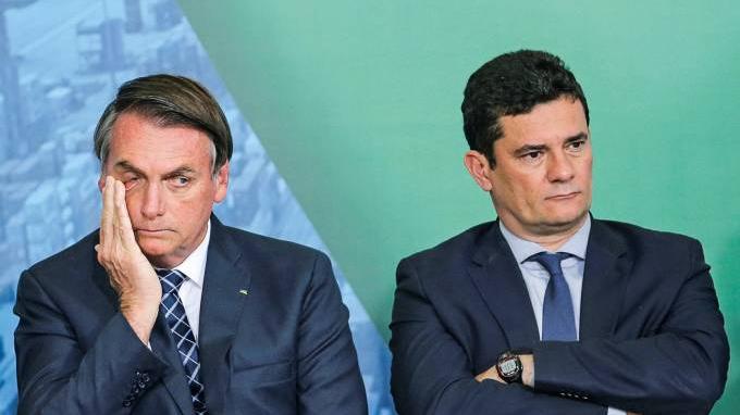 O presidente Jair Bolsonaro está sentado ao lado do ex-ministro da Justiça e ex-aliado Sergio Moro.