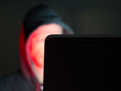 Homem encapuzado mexendo em computador