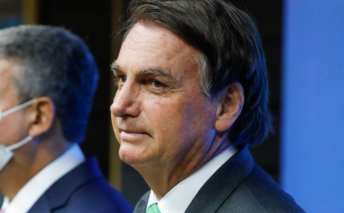 Jair Bolsonaro sem máscara ao lado de pessoa usando máscara