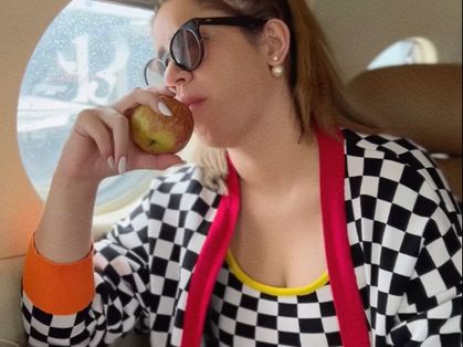 Cantora Marília Mendonça dentro de um táxi aéreo comendo uma maçã.