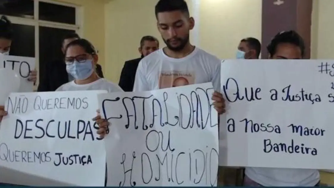 Família de wanderson de holanda com cartazes protestando sobre a morte do soldado