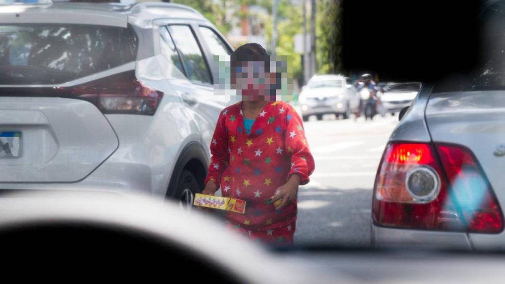 Criança vestida de palhaço vendendo doces na rua