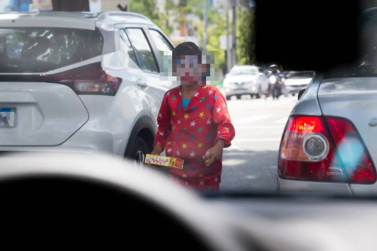 Criança vestida de palhaço vendendo doces na rua