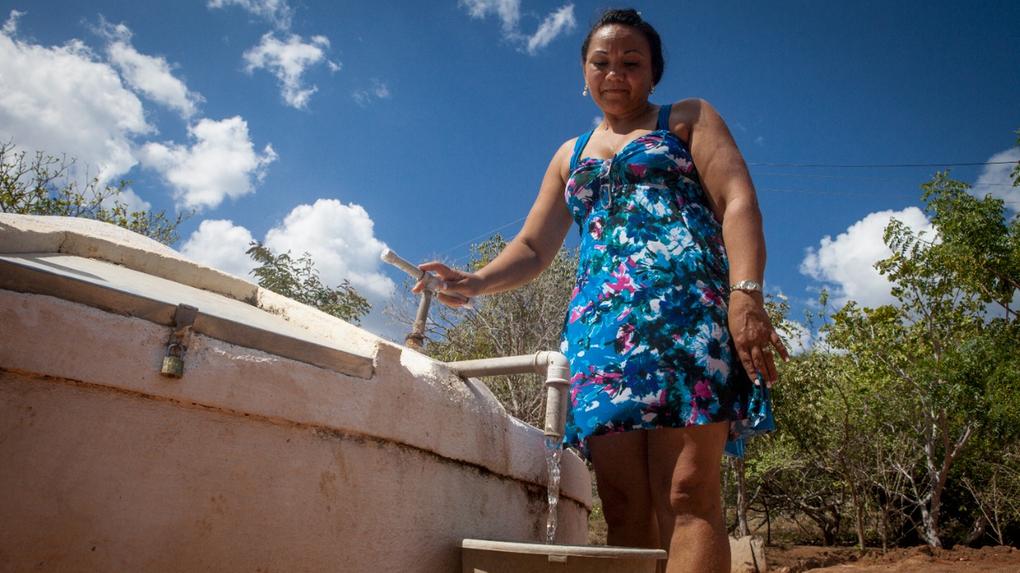 Mulher tirando água de cisterna no Ceará