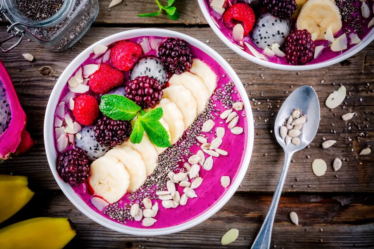 Bacia com smoothie de pitaya e frutas como amora, banana e folhas de hortelã