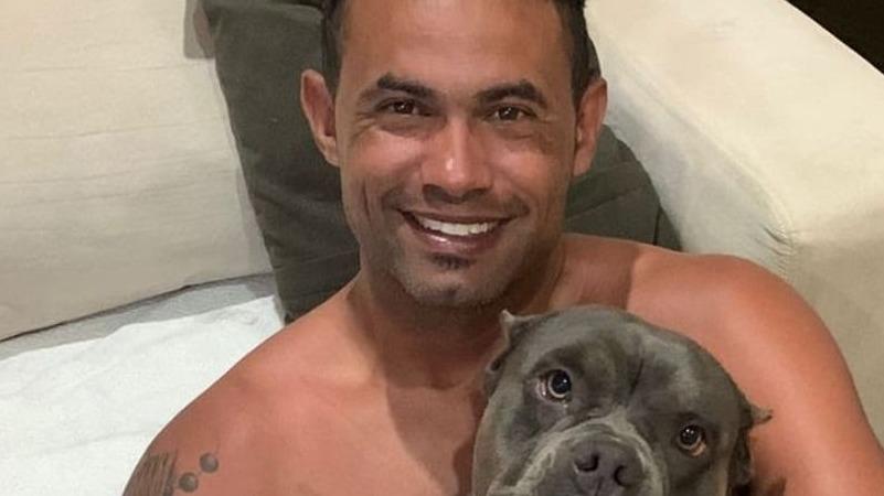 O goleiro Bruno Fernandes posa ao lado de uma cadela preta da raça pitbull.