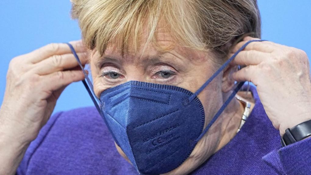 Angela Merkel, chanceler da Alemanha, colocando máscara azul sobre o rosto