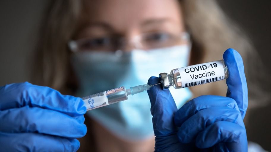 Imagem mostra uma mulher segurando uma vacina contra a Covid-19.