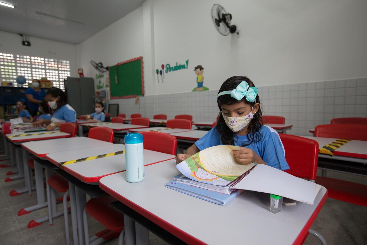 Estudante foleia livro sentada em carteira em escola municipal de Fortaleza