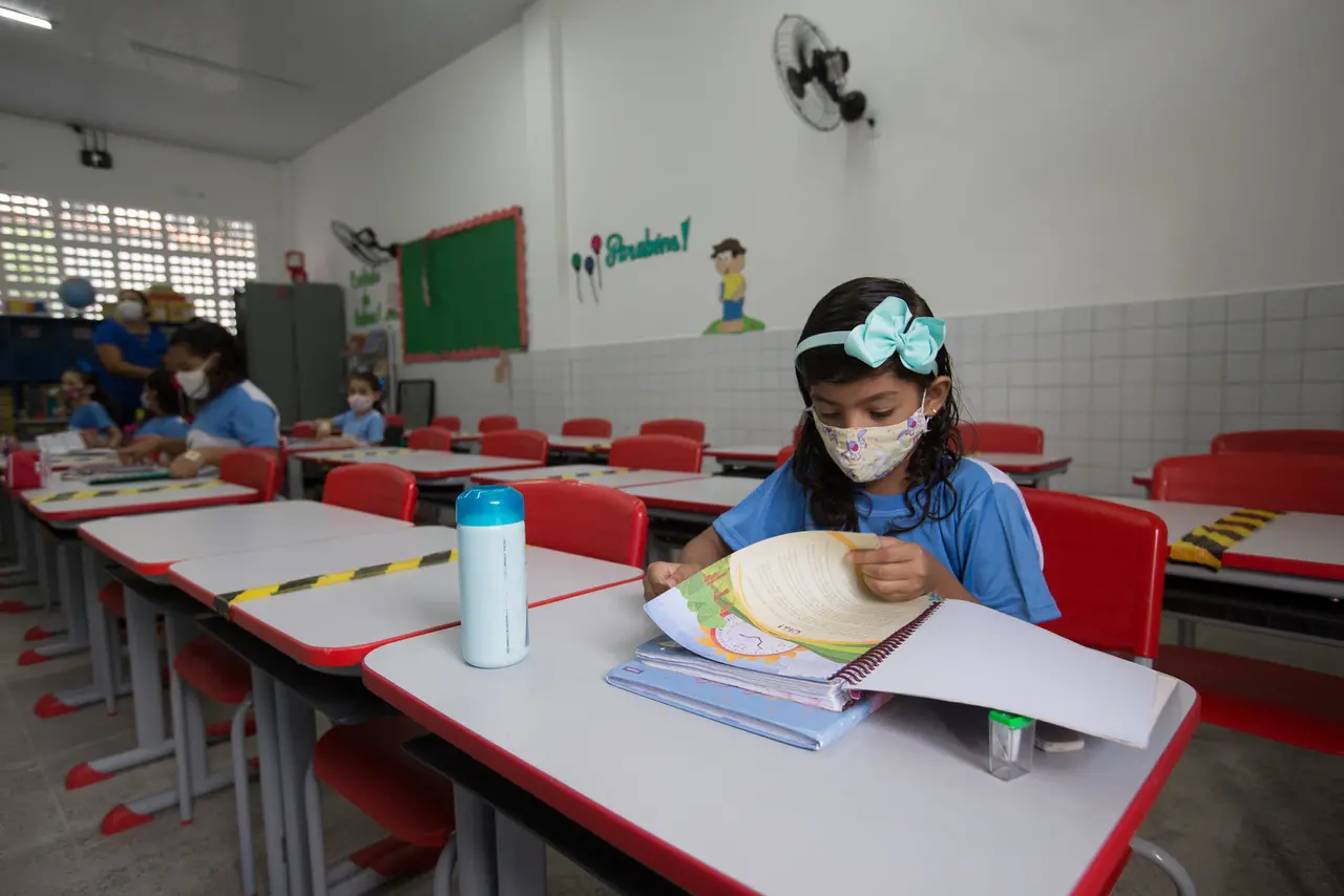 Estudante foleia livro sentada em carteira em escola municipal de Fortaleza
