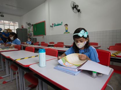 Estudante foleia livro sentada em carteira em escola municipal de Fortaleza