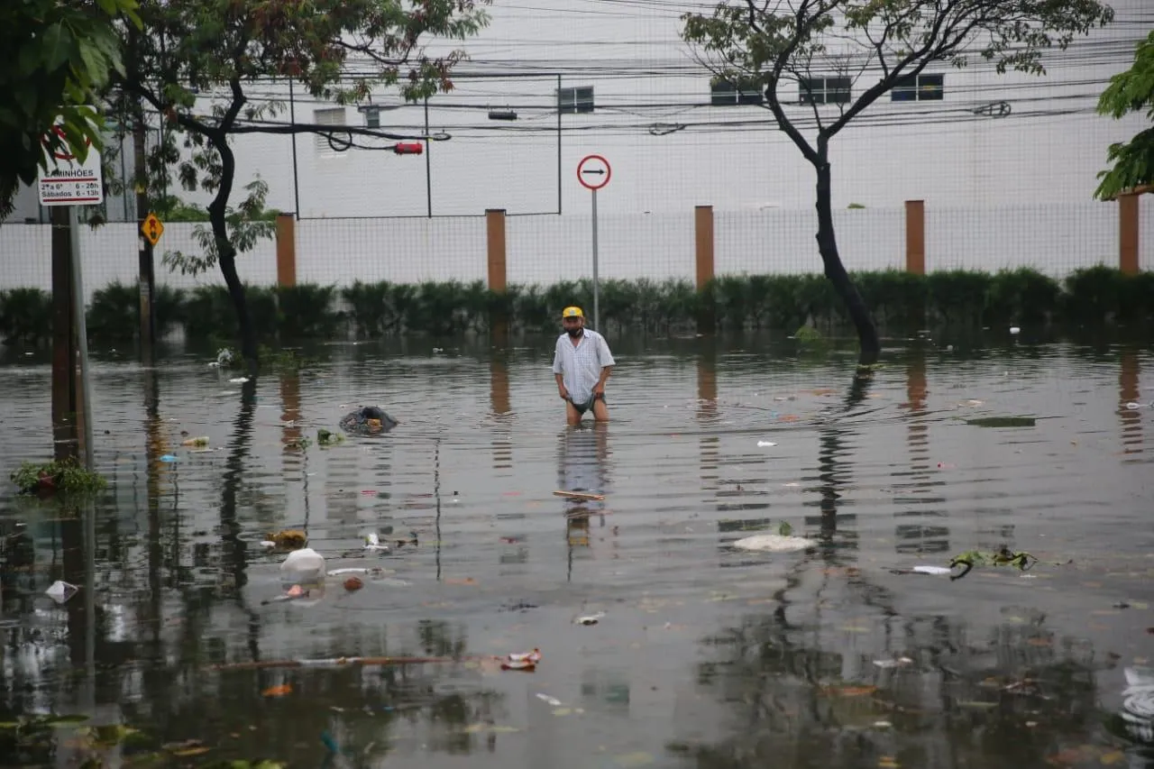 Pedestre tenta atravessar Av. Heráclito Graça alagada após forte chuva