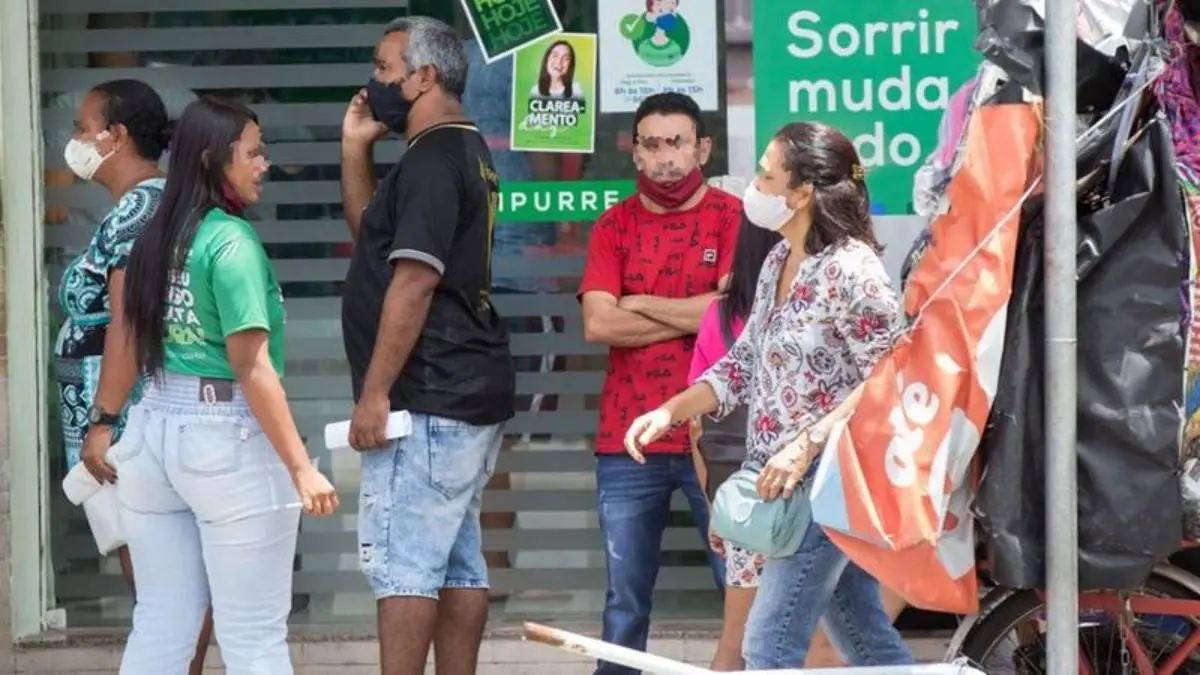 Pessoas com máscara e sem máscara de proteção formam fila em Fortaleza