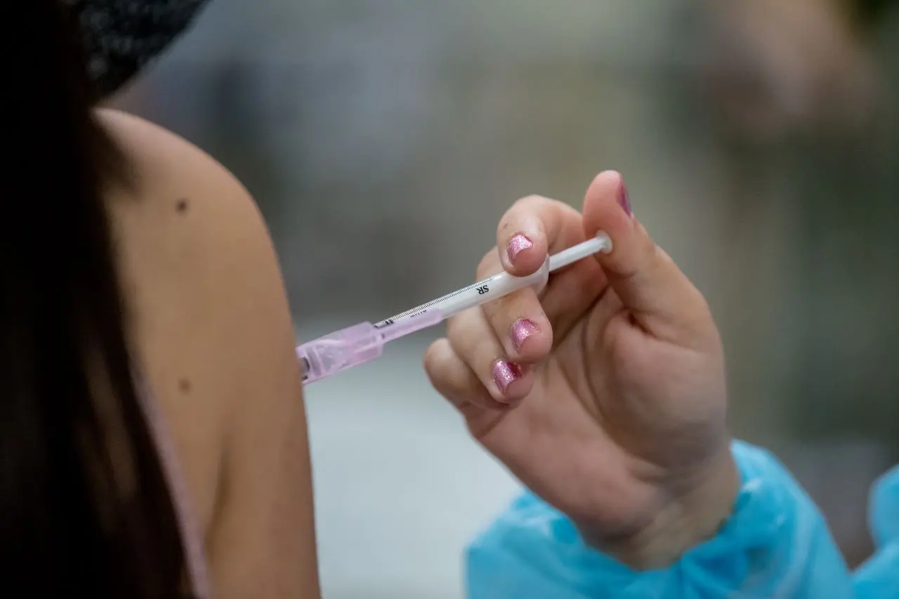 mão segura seringa injetando vacina contra a Covid-19 em braço