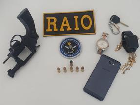 ama, munições, celular, relógio e objetos em uma mesa com a placa do raio da PMCE