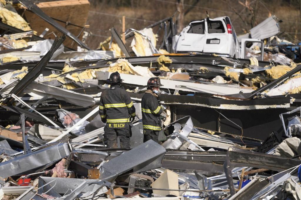 Dois bombeiros vasculham os escombros de uma fábrica destruída por tornados em Mayfield.