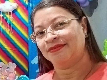 Maria da Solidade dos Santos, professora morta em Massapê, usando óculos em frente a cenário infantil