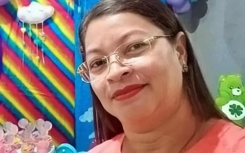 Maria da Solidade dos Santos, professora morta em Massapê, usando óculos em frente a cenário infantil