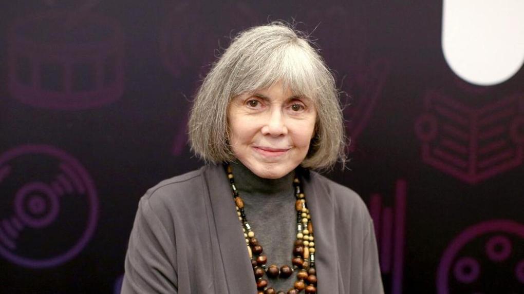 Escritora Anne Rice usando roupa cinza e colar com contas bronzeadas