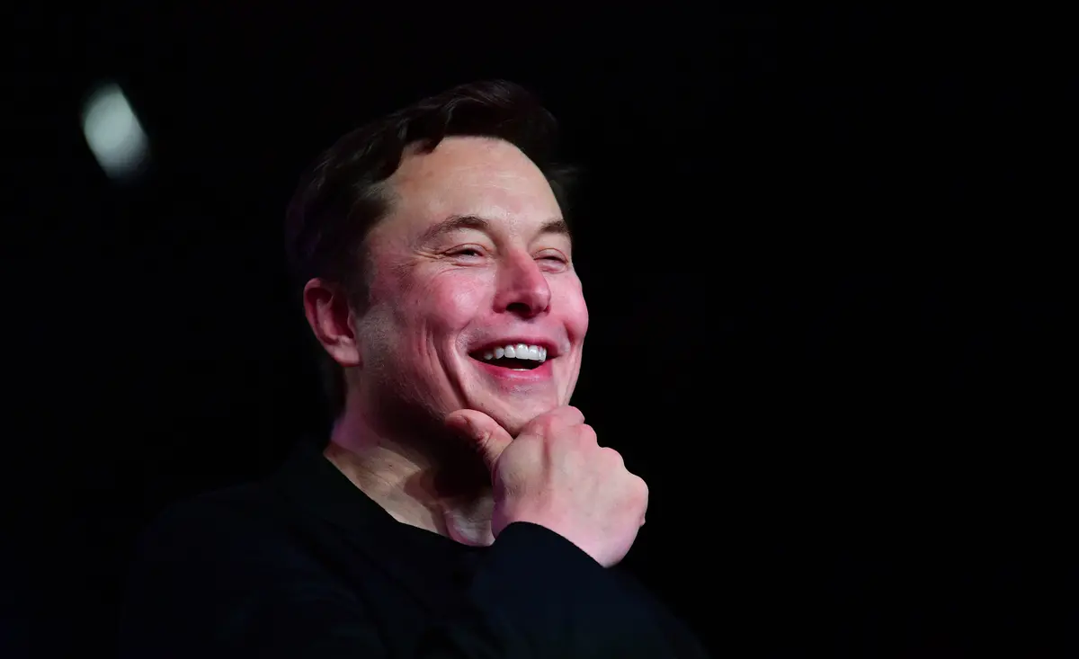 Musk sorri e coloca a mão no queixo