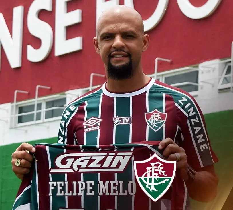 felipe melo veste a camisa do fluminense e segura outra, na sede do clube