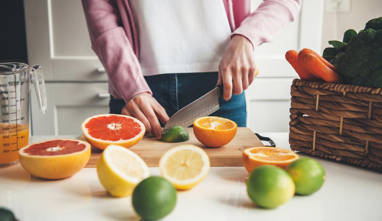 Foto de mulher cortando frutas para fazer suco em casa na cozinha