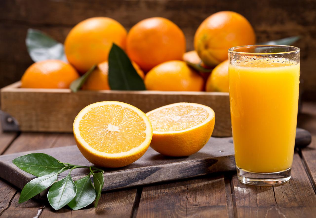 Copo de suco de laranja fresco com frutas frescas na mesa de madeira