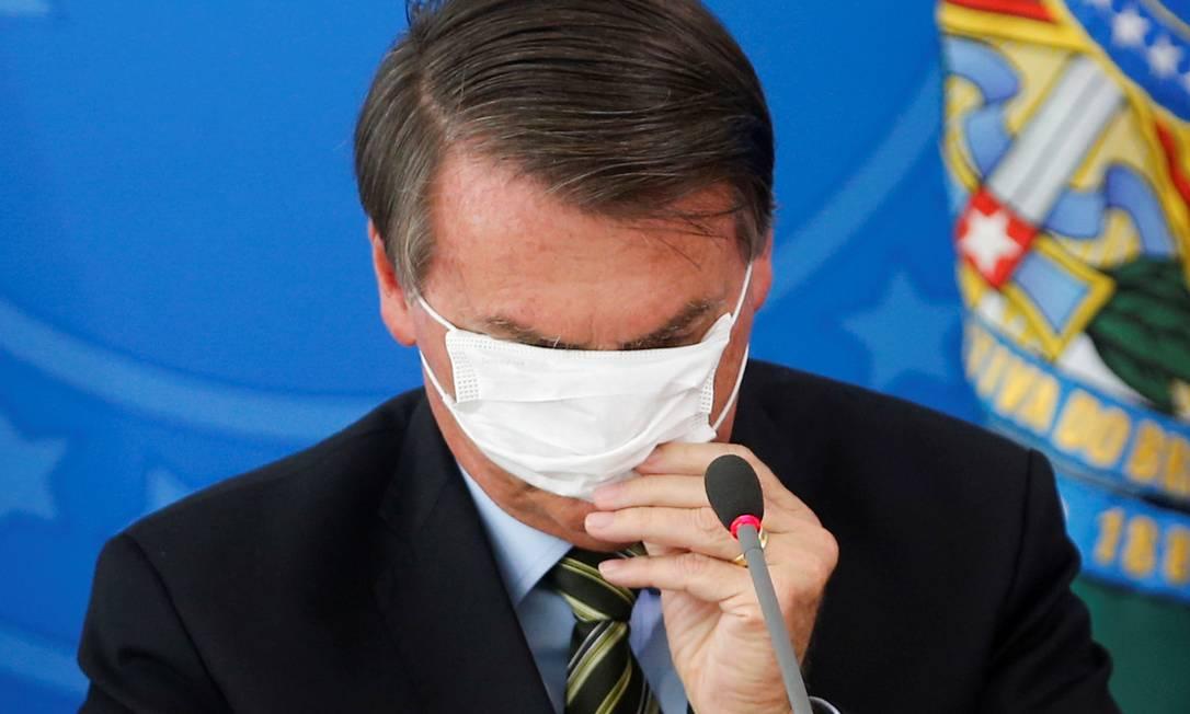 A imagem mostra Bolsonaro colocando a máscara de forma errada, sobre os olhos.