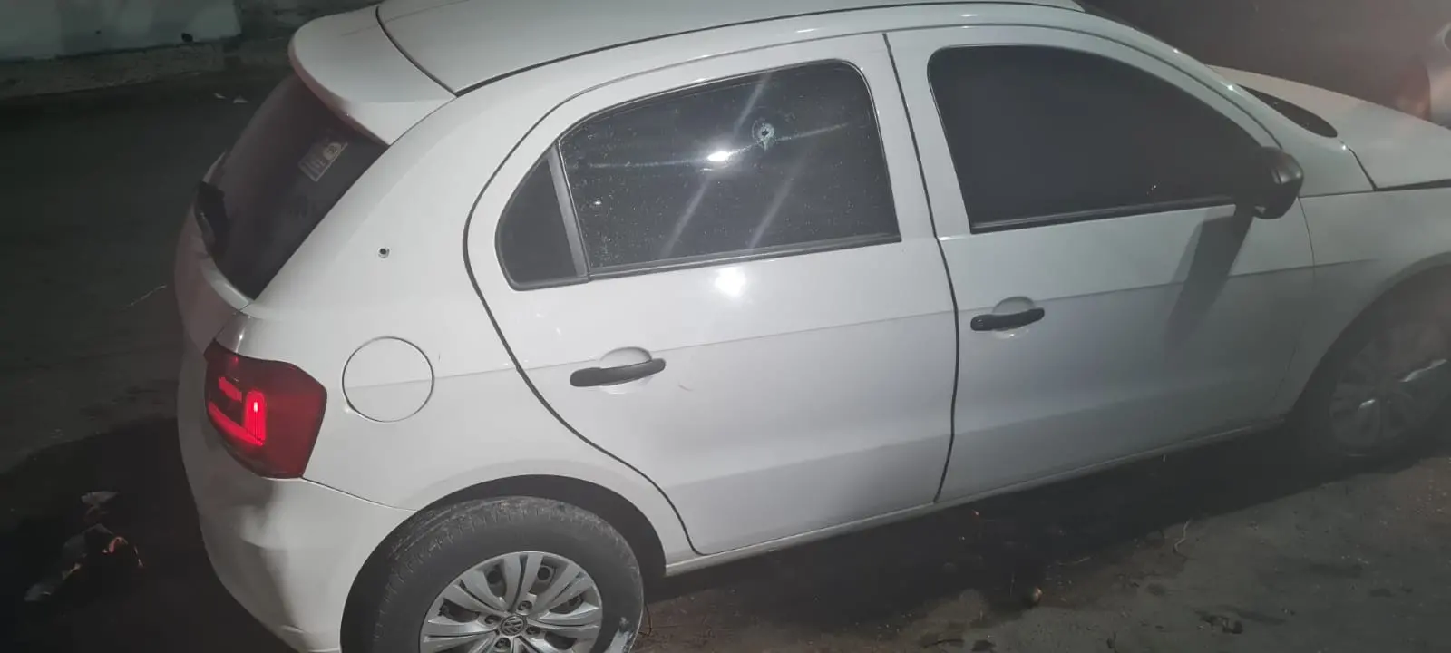 Carro branco com marcas de tiros no vidro