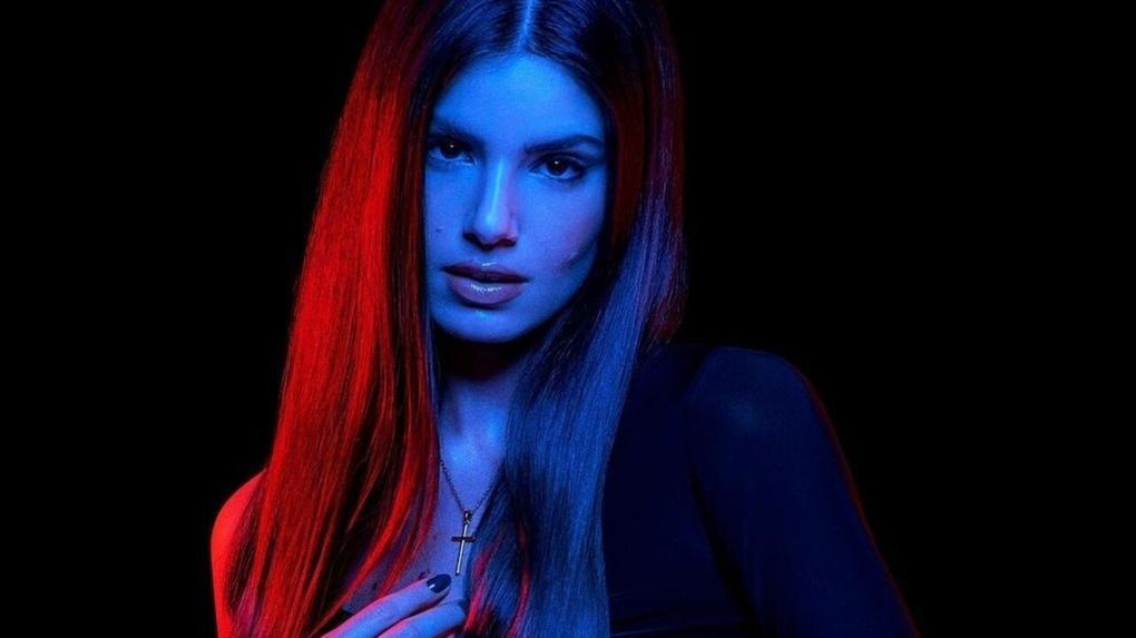 Camila Queiroz maquiada, iluminada por luzes azul e vermelha
