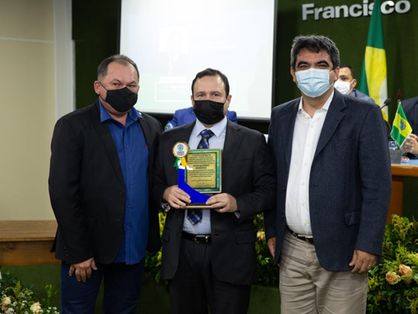 Igor Queiroz com o título de cidadão honorário cascavelense, acompanhado do vereador Gladson Bezerra (à esquerda) e do prefeito de Cascavel, Tiago Ribeiro (à direita)