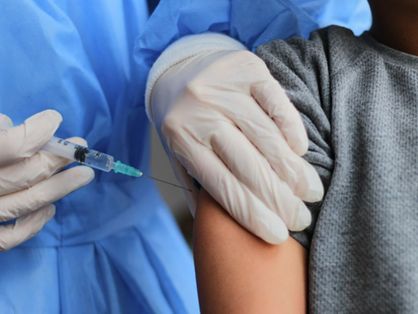 Profissional de saúde aplicando vacina contra Covid-19 em braço de criança