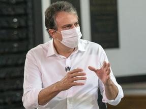 Governador do Ceará, Camilo Santana, com blusa branca e máscara de proteção facial durante entrevista