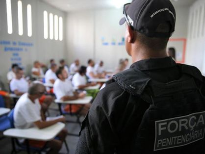 Policial penal observa detentos em sala de aula penitenciária