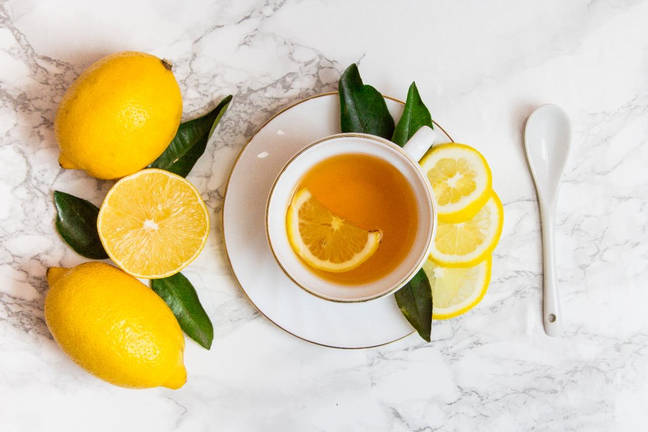 Xícara branca contendo chá de limão, fotografada de cima
