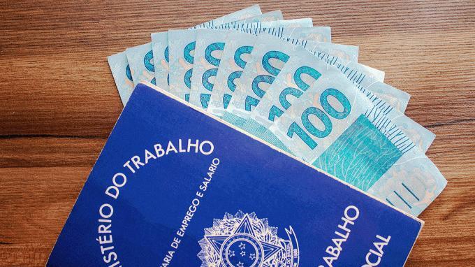 Carteira de Trabalho com c&eacute;dulas de 100 reais dentro