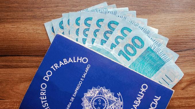 Carteira de Trabalho com cédulas de 100 reais dentro