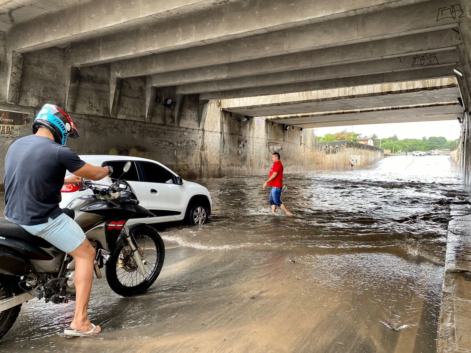 O caminhoneiro Ciro Quinto (de vermelho) passou 45 minutos procurando a placa de seu veículo sob a água que alagava o túnel