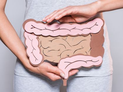 Imagem de uma mulher segurando um papel que representa o intestino grosso sobre fundo cinza