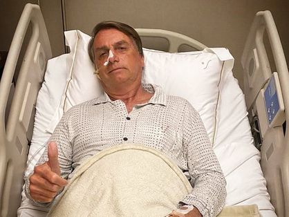 bolsonaro deitado numa maca hospitalar, sinalizando legal