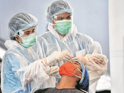 Duas enfermeiras fazem teste com swab nasal em um paciente