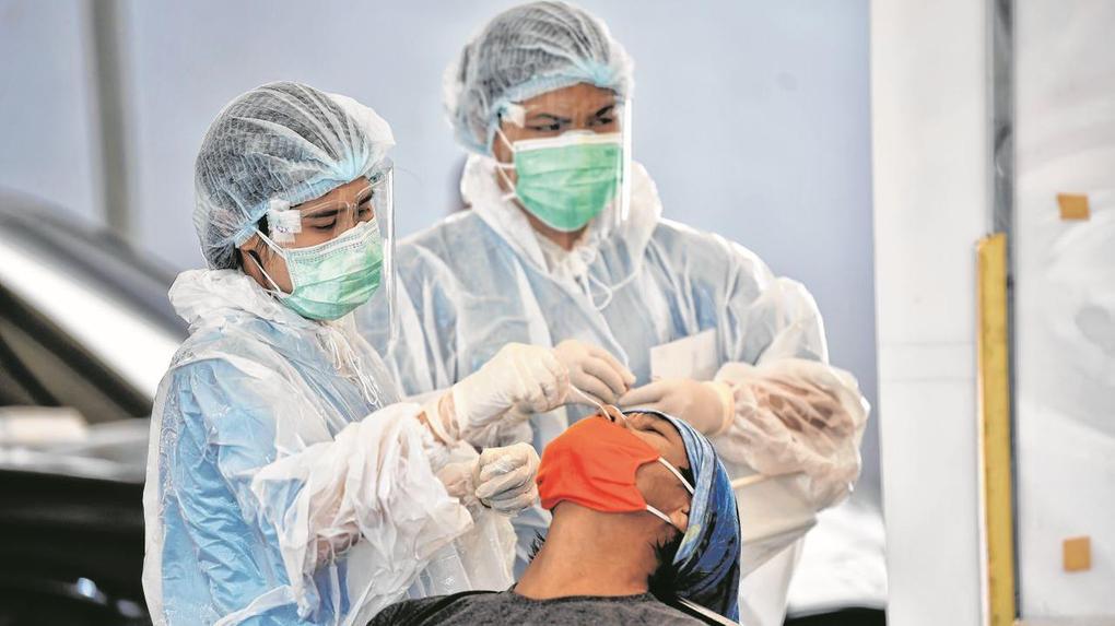 Duas enfermeiras fazem teste com swab nasal em um paciente