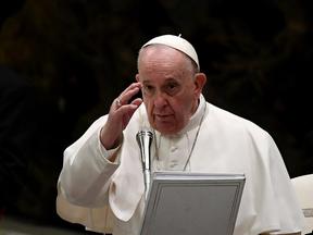 Papa Francisco com mão erguida em frente a púlpito com microfone