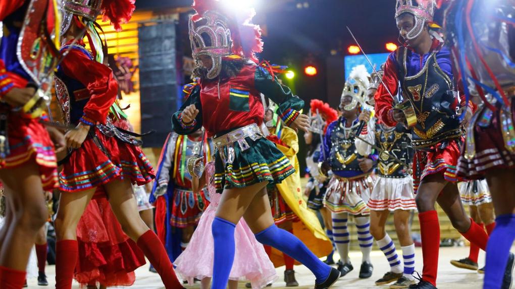 Grupo de pessoas dançando com vestes tradicionais de reisado popular, festividade do Dia de Reis